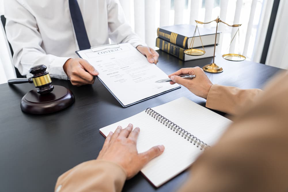 A lawyer or judge presents contract documents to a client, symbolizing law and legal services. A lawyer or judge presents contract documents to a client, symbolizing law and legal services.
