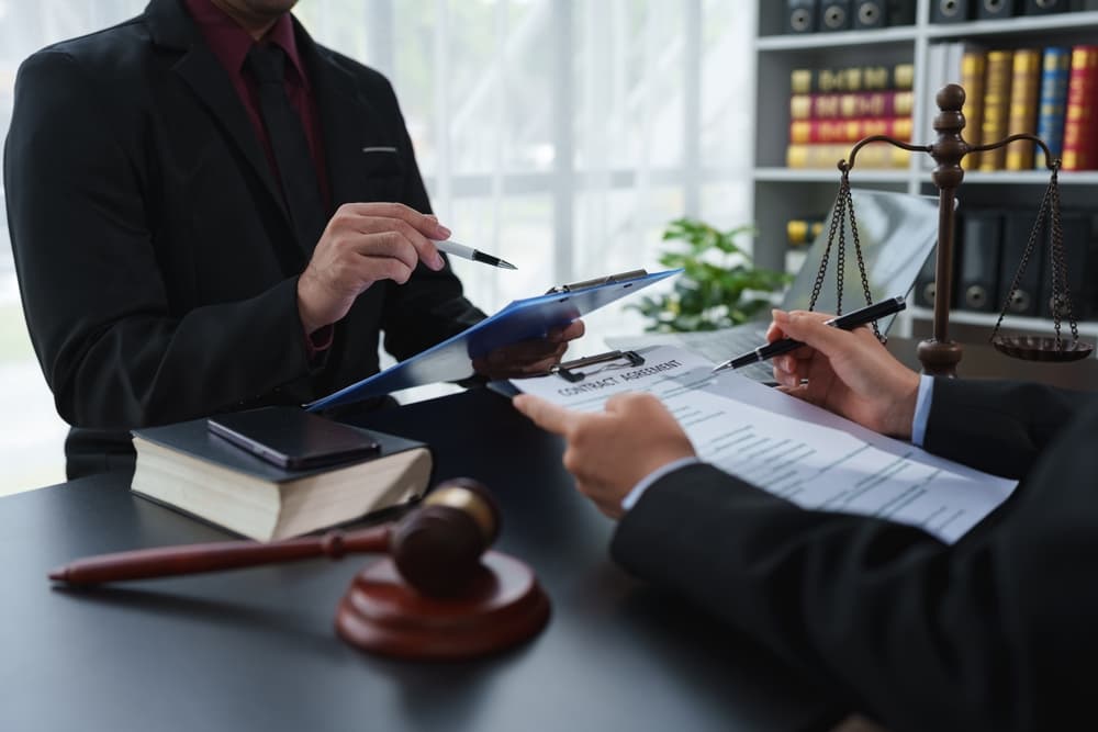 A legal advisor reviews the statute of limitations and clarifies contract details before signing. Consultation between attorney and business client at a legal services firm.