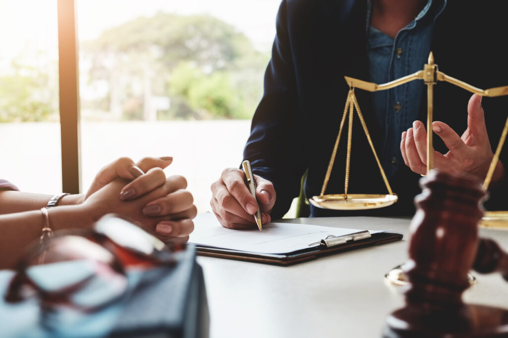 Lawyer consulting client with legal documents, gavel, and scales of justice on desk Lawyer consulting client with legal documents, gavel, and scales of justice on desk