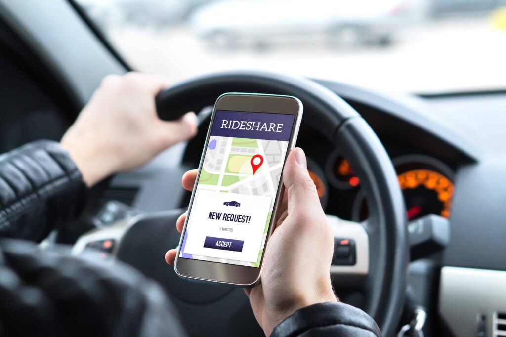 Rideshare driver holding smartphone with ride request app while driving car Rideshare driver holding smartphone with ride request app while driving car