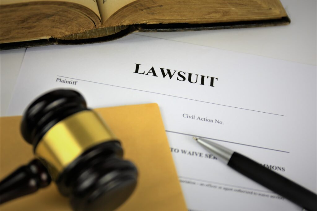 Lawsuit document with judge’s gavel, legal envelope, and pen on desk Lawsuit document with judge’s gavel, legal envelope, and pen on desk